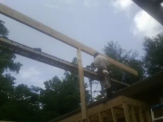 Carpenter setting a ridge beam over a new addition frame — Ice Dam Removal by Roofing Brothers in Assonet