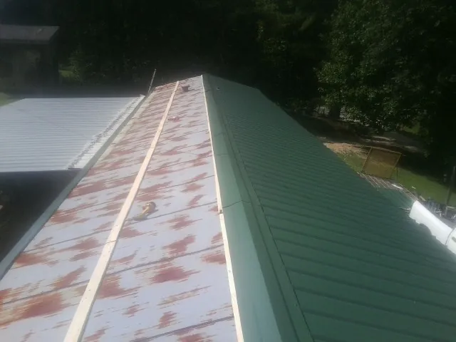 Old rusted panels beside newly installed green metal roofing — Wind Damage Roof Repair by Roofing Brothers in Assonet