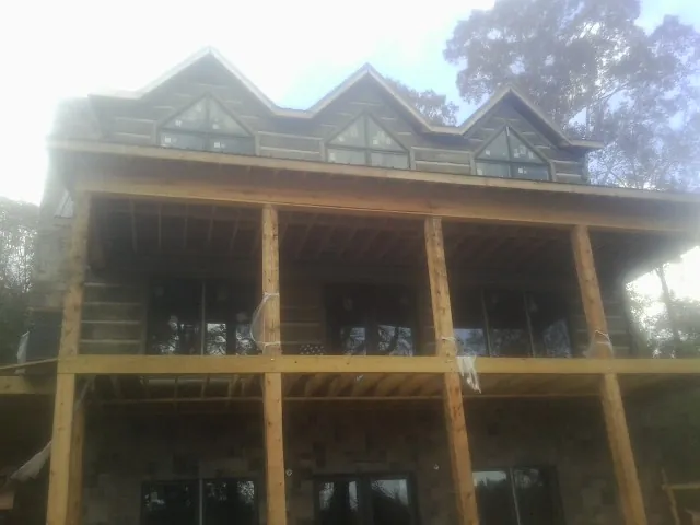 Dormers and porch framing on a large log home under construction — Roof Coating work by our crew in Assonet