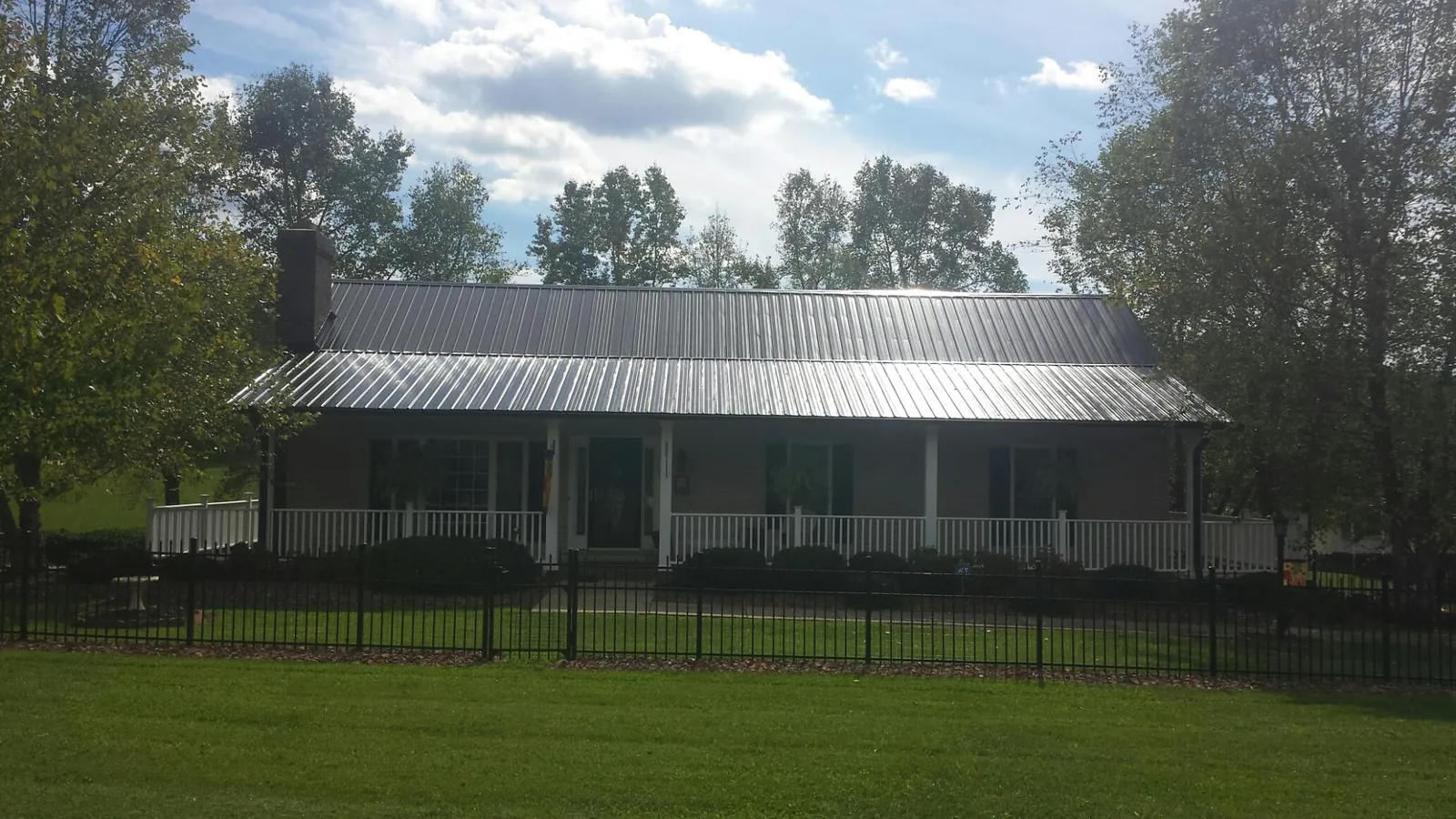 Gray metal roof on a brick ranch with a full width front porch — Gutter Guard Installation work by our crew in Assonet