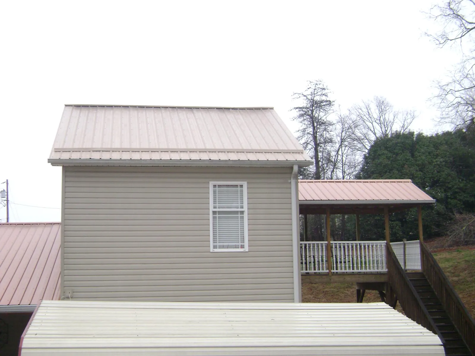 Tan metal roofs on a two story addition and attached porch, from a Roof Replacement job in Assonet