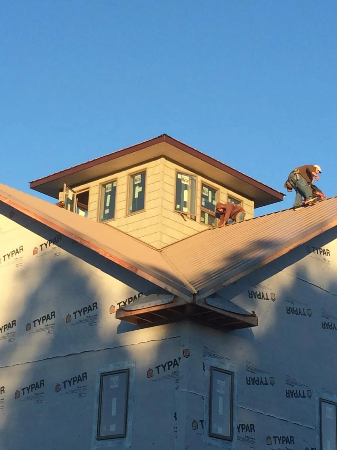 Roofers working around a rooftop cupola on a new metal roof at sunset — Roof Waterproofing in Assonet by Roofing Brothers
